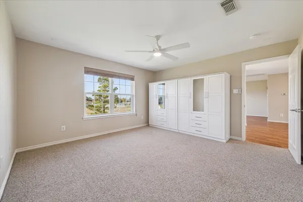 an empty room with chandelier fan and windows