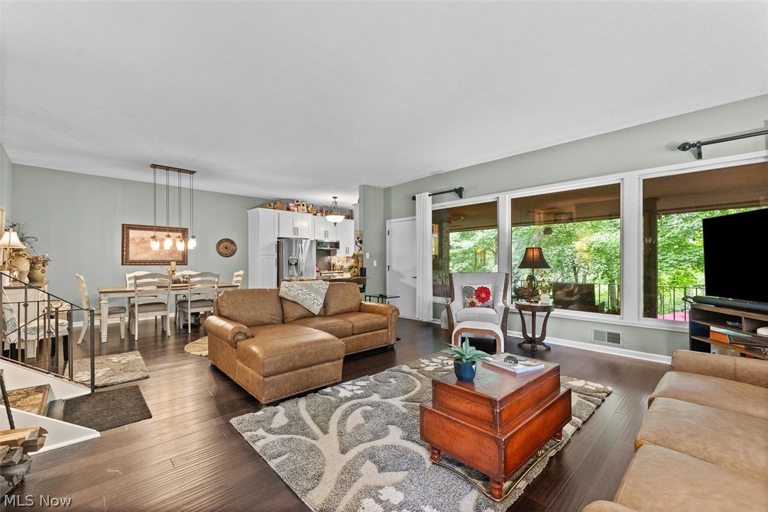 171 Granger Road, Unit 107 Medina, OH 44256 - Photo 10 of 41 Open-concept living area with dark Bamboo wood flooring, a wall of large windows, and a dining area featuring a linear pendant light fixture