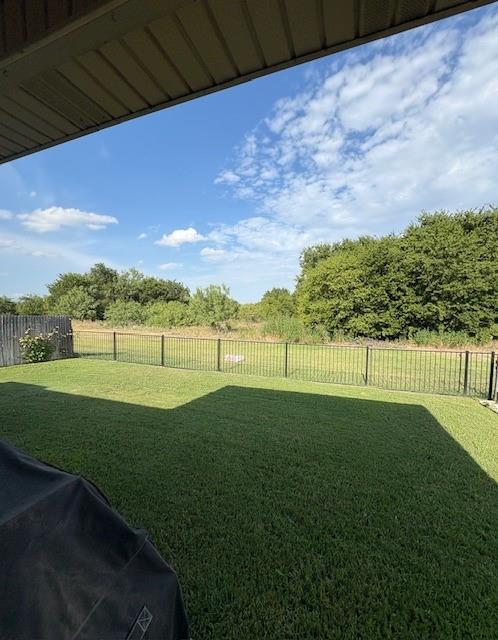 14308 Polo Ranch Street Fort Worth, TX 76052 - Photo 18 of 19 Expansive green lawn featuring a black wrought iron fence and mature perimeter foliage
