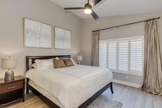 a large bed sitting in a bedroom next to a window and a lamp