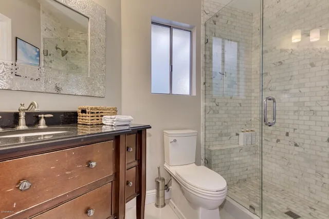 a bathroom with a granite countertop sink toilet and shower