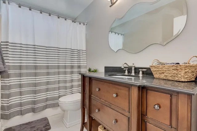 a bathroom with a granite countertop toilet sink and mirror