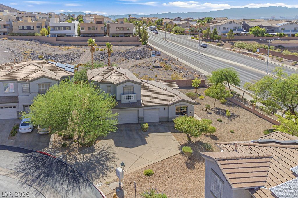 754 Solitude Point Avenue Henderson, NV 89012 - Photo 3 of 38 An aerial perspective showcases a charming residence with an attached garage and desert landscaping.