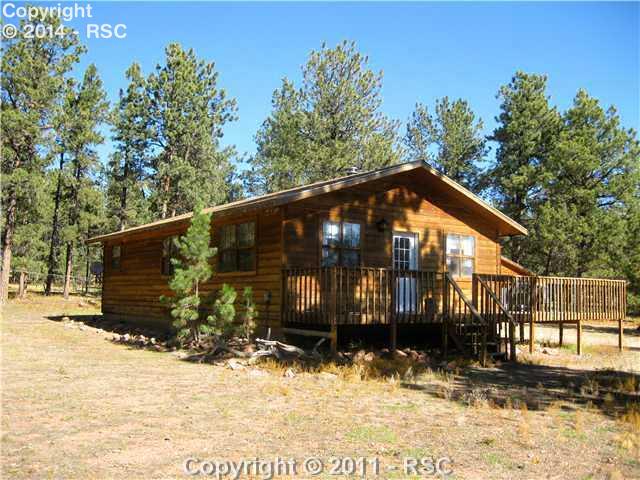 The cabin on this 20-acre parcel is surrounded by mature evergreen trees.