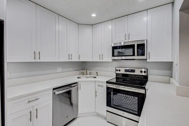 a kitchen with cabinets appliances a sink and a counter top