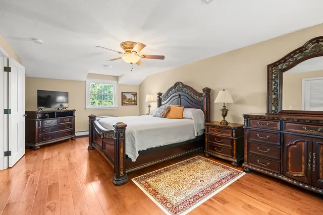 a bedroom with a bed dresser and a wooden floor