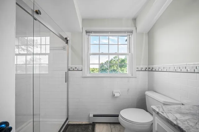 a white toilet sitting next to a window in a bathroom