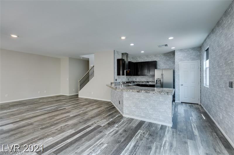 5475 Ordesa Valley Road Las Vegas, NV 89148 - Photo 26 of 35 A contemporary open-concept space features resilient plank flooring and a sleek kitchen with a functional breakfast bar.