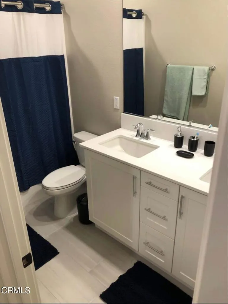 1107 Delpy View Point Vista, CA 92084 - Photo 3 of 8 a bathroom with a sink a toilet a mirror and shower curtain