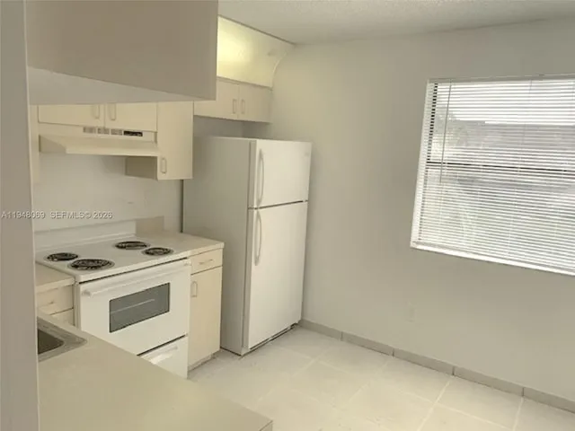 a kitchen with a stove a refrigerator and a white cabinets