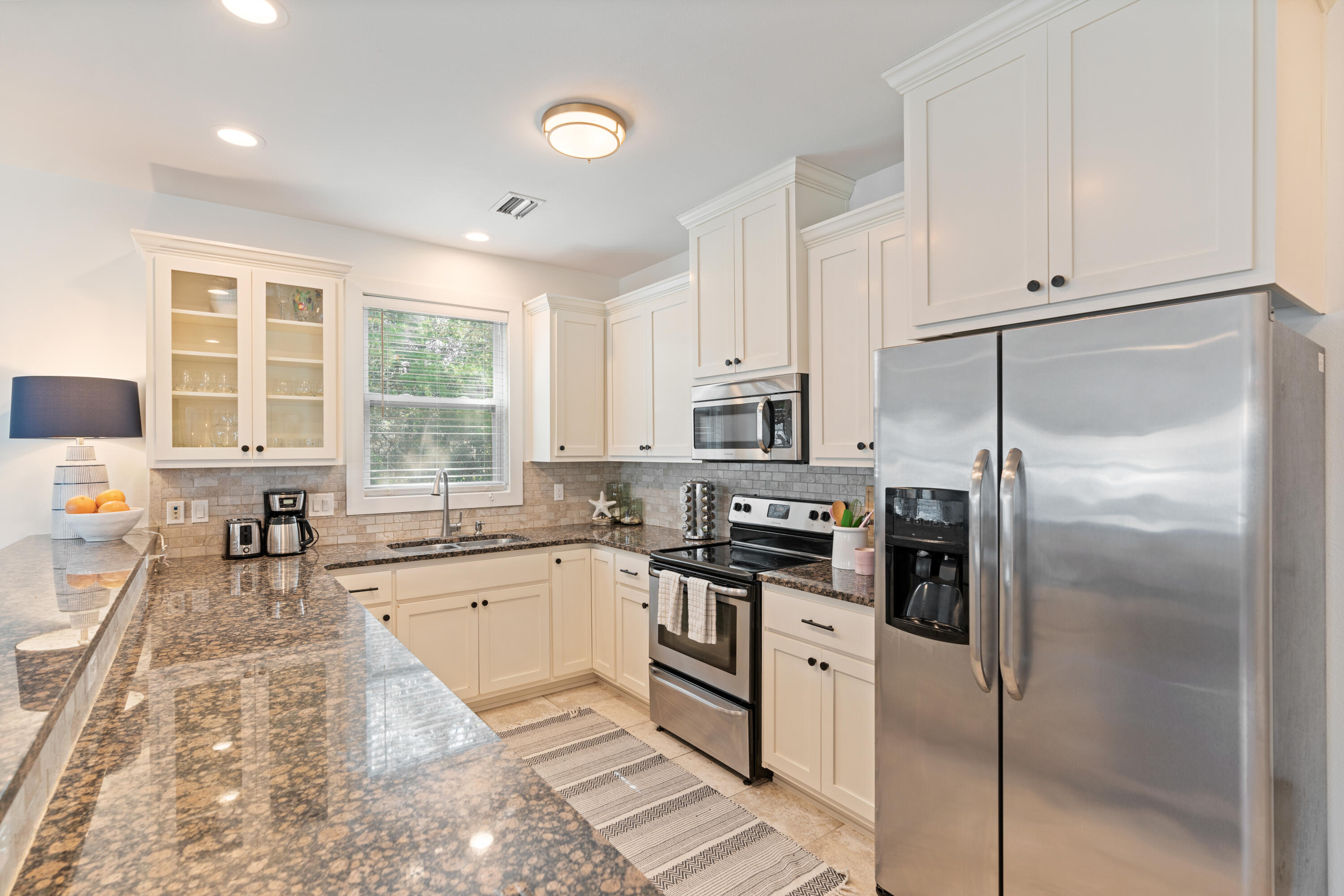 83 Brown Street Santa Rosa Beach, FL 32459 - Photo 12 of 42 a kitchen with stainless steel appliances granite countertop a stove a refrigerator a sink a counter space and cabinets