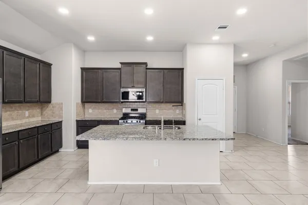 a large kitchen with stainless steel appliances kitchen island granite countertop a sink and cabinets
