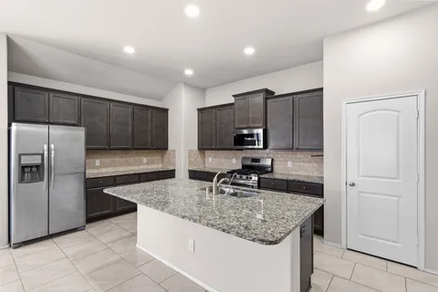 a kitchen with kitchen island granite countertop a sink stove and refrigerator