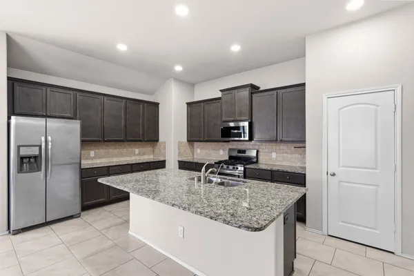 a kitchen with kitchen island granite countertop a sink stove and refrigerator