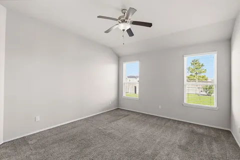 an empty room with windows and fan