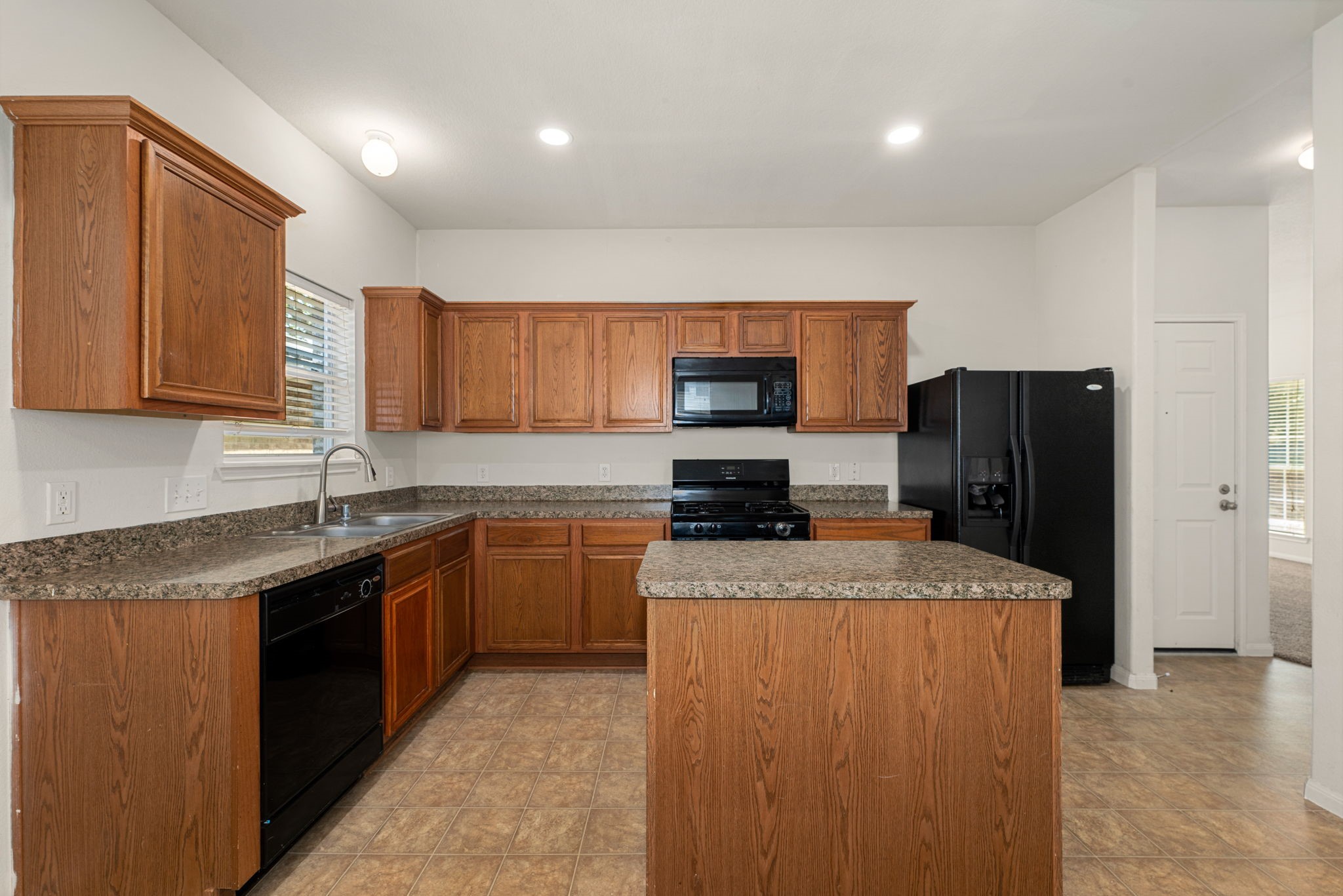 20927 Roxette Court Humble, TX 77338 - Photo 3 of 19 Rich granite countertops and a generous center island anchor the kitchen, flowing effortlessly into the adjoining dining space for easy entertaining.