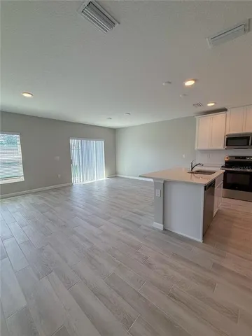 a kitchen with stainless steel appliances granite countertop a stove a sink dishwasher and a refrigerator with wooden floor