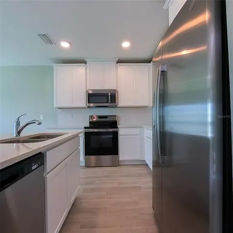 a view of kitchen with wooden floor and electronic appliances