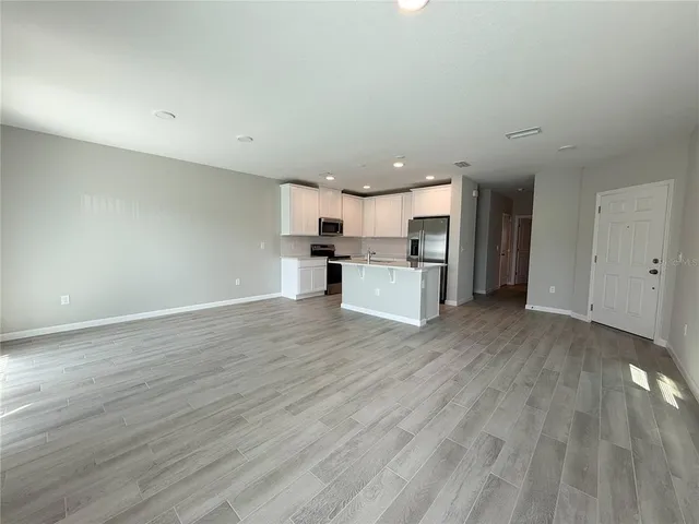 a view of kitchen with stainless steel appliances granite countertop a stove top oven a sink and a microwave oven on the wooden floor