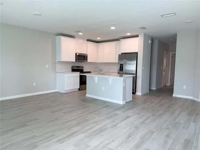 a kitchen with a refrigerator a microwave a sink and cabinets
