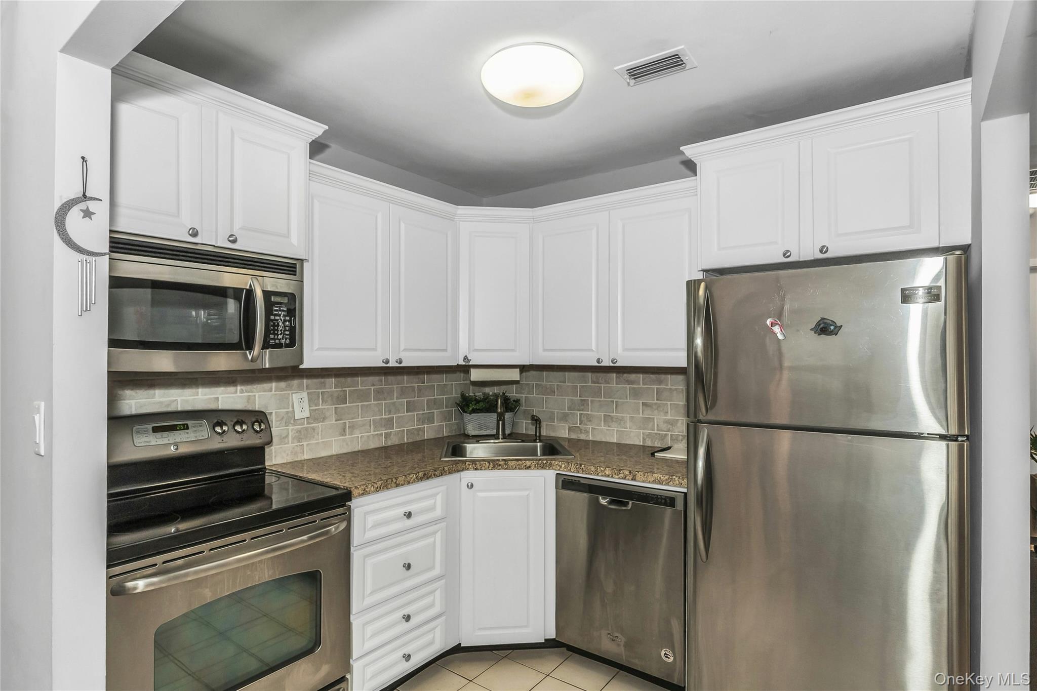 650 Newbridge Road, Unit 9 East Meadow, NY 11554 - Photo 5 of 9 a kitchen with white cabinets and stainless steel appliances