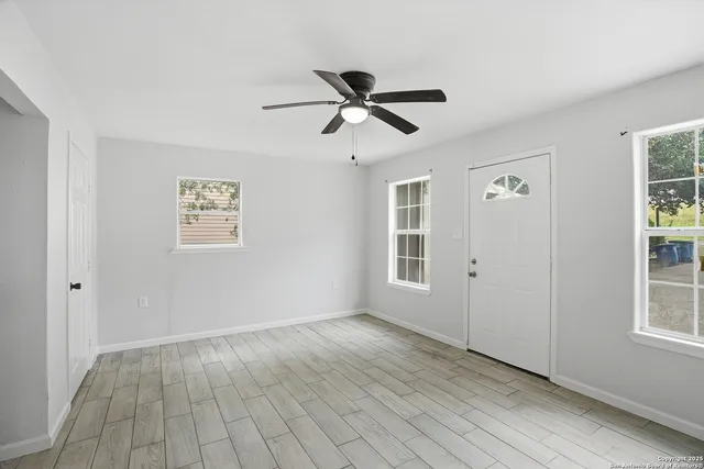 a view of empty room with wooden floor and fan