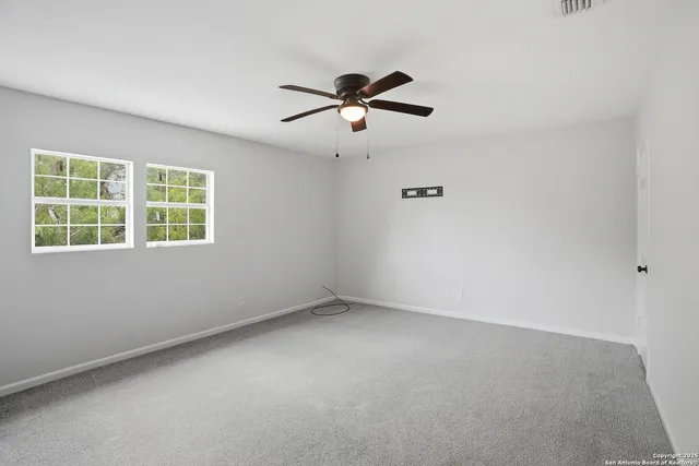 an empty room with a window and a fan