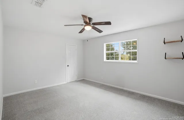 an empty room with windows and fan