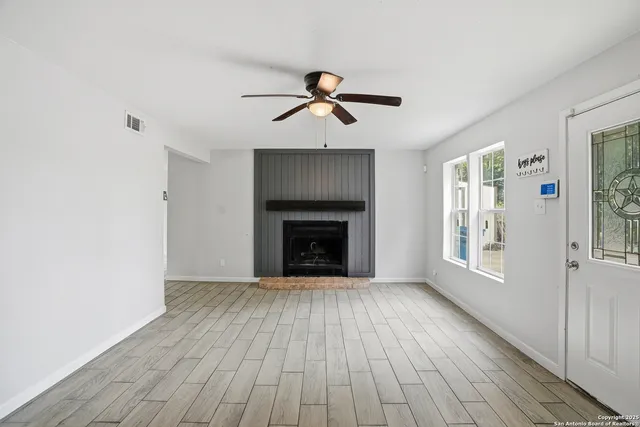 a view of an empty room with wooden floor fireplace and a window
