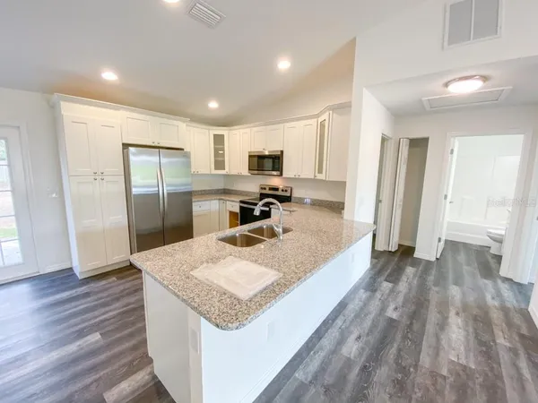 a large kitchen with a center island wooden floor and stainless steel appliances
