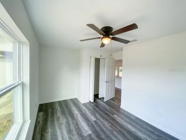 a view of empty room with wooden floor and fan