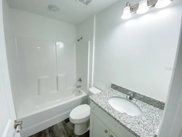 a bathroom with a granite countertop sink a toilet and bathtub