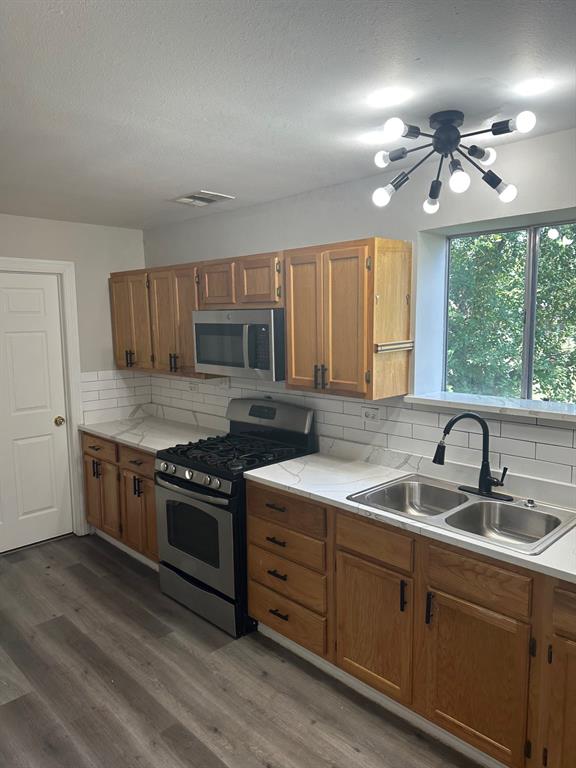 8280 Highway 78 Blue Ridge, TX 75424 - Photo 7 of 21 Kitchen with stainless steel range, tasteful backsplash, dark wood-style flooring, a textured ceiling, and brown cabinetry