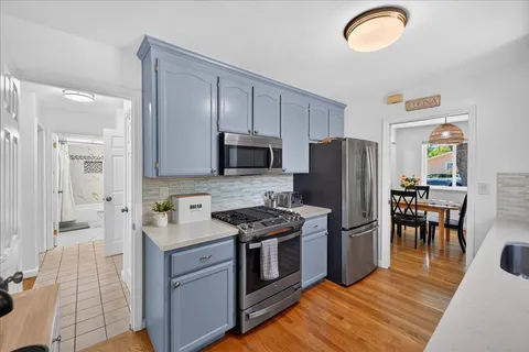a kitchen with stainless steel appliances granite countertop a stove a sink dishwasher a refrigerator and a microwave oven with wooden floor
