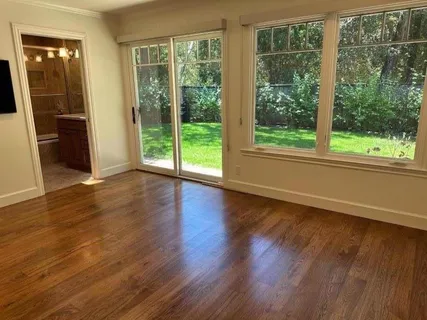 a view of an empty room with wooden floor and a window
