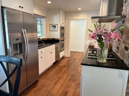 a kitchen with stainless steel appliances granite countertop a refrigerator a sink a stove and white cabinets