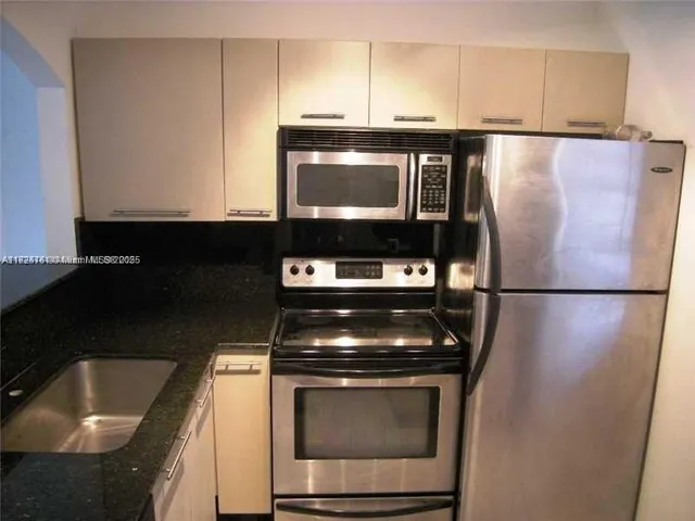 a kitchen with granite countertop a refrigerator stove and microwave