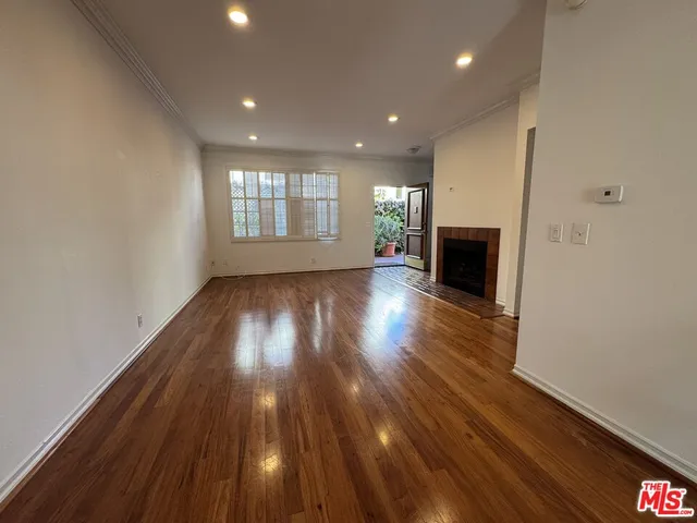 a view of empty room with wooden floor and fireplace