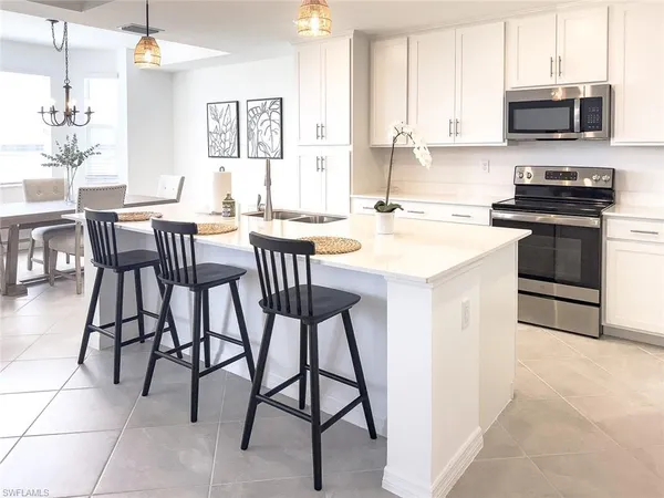 a kitchen with stainless steel appliances kitchen island granite countertop a table chairs sink and cabinets