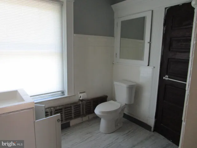 a bathroom with a toilet a sink a window and mirror