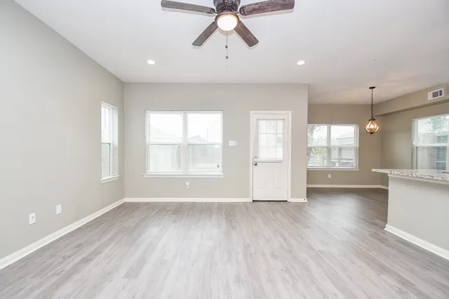 a view of an empty room with a window and wooden floor