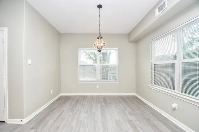 a view of an empty room with a window and wooden floor
