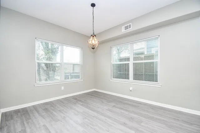 an empty room with wooden floor exposed radiator and windows