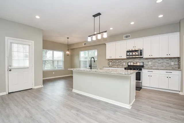 a kitchen with stainless steel appliances granite countertop a sink cabinets and wooden floor