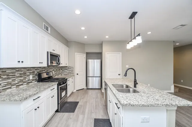 a kitchen with stainless steel appliances granite countertop a sink a stove and a wooden floors