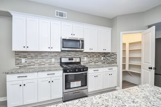 a kitchen with white cabinets and appliances