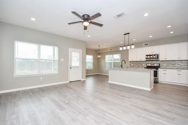 a large kitchen with cabinets wooden floor and stainless steel appliances