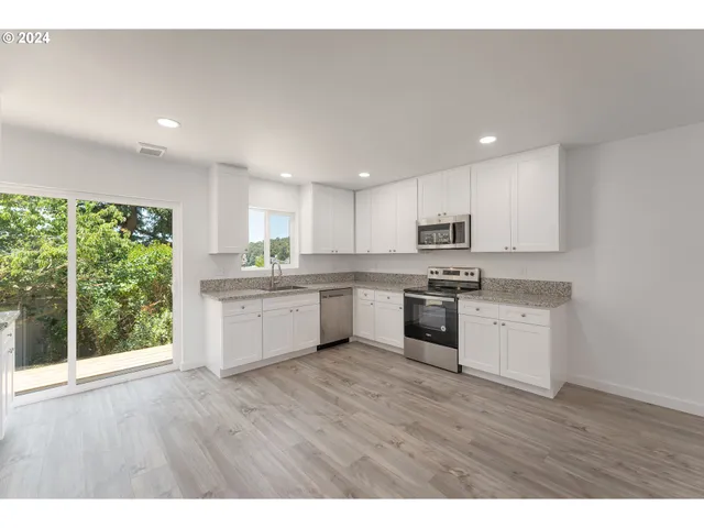 a kitchen with wooden floors stainless steel appliances and white cabinets