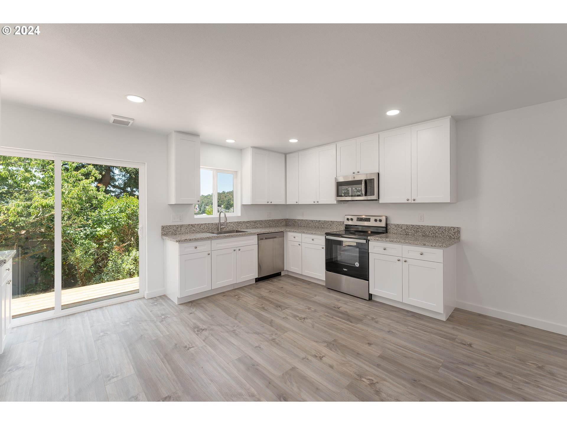 1237 Southeast Washington Avenue Roseburg, OR 97470 - Photo 14 of 28 a kitchen with wooden floors stainless steel appliances and white cabinets