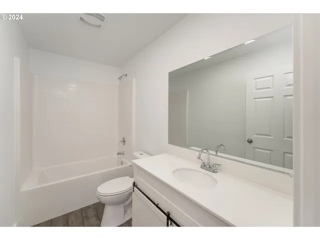 a bathroom with a bathtub shower sink vanity mirror and toilet